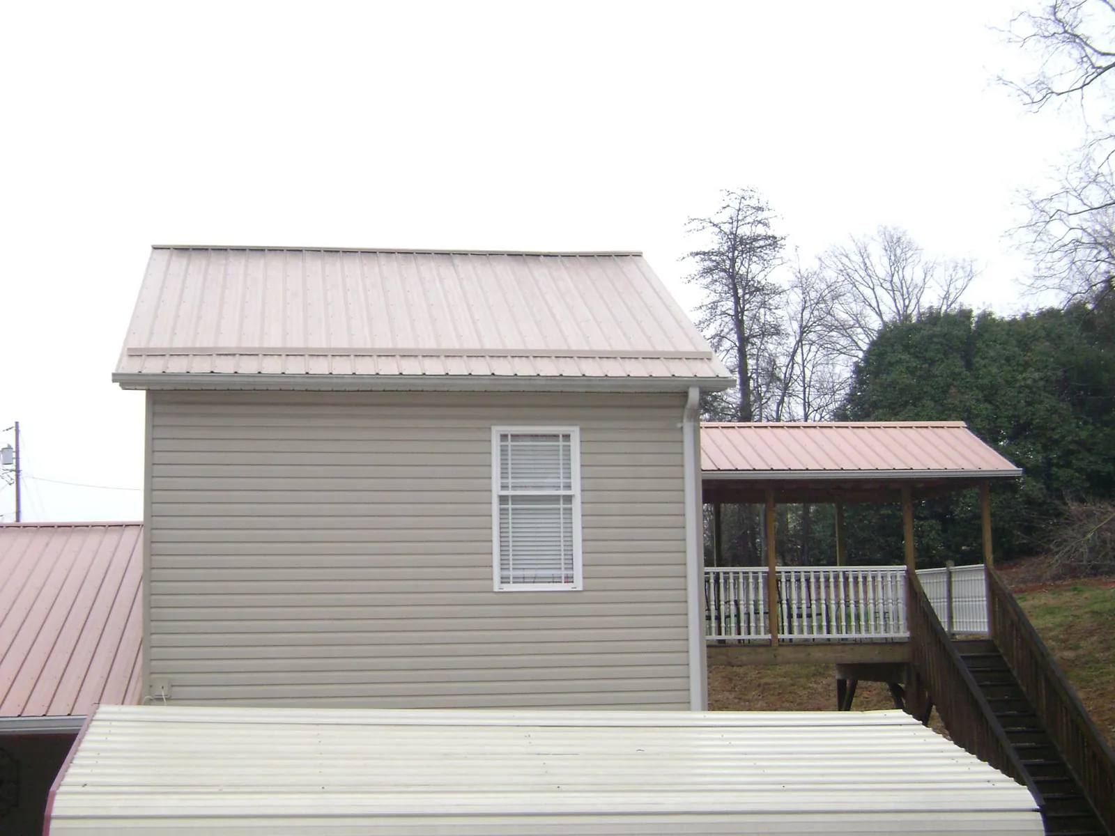 Tan metal roofs on a two story addition and attached porch, from a Roof Replacement job in Fredericksburg