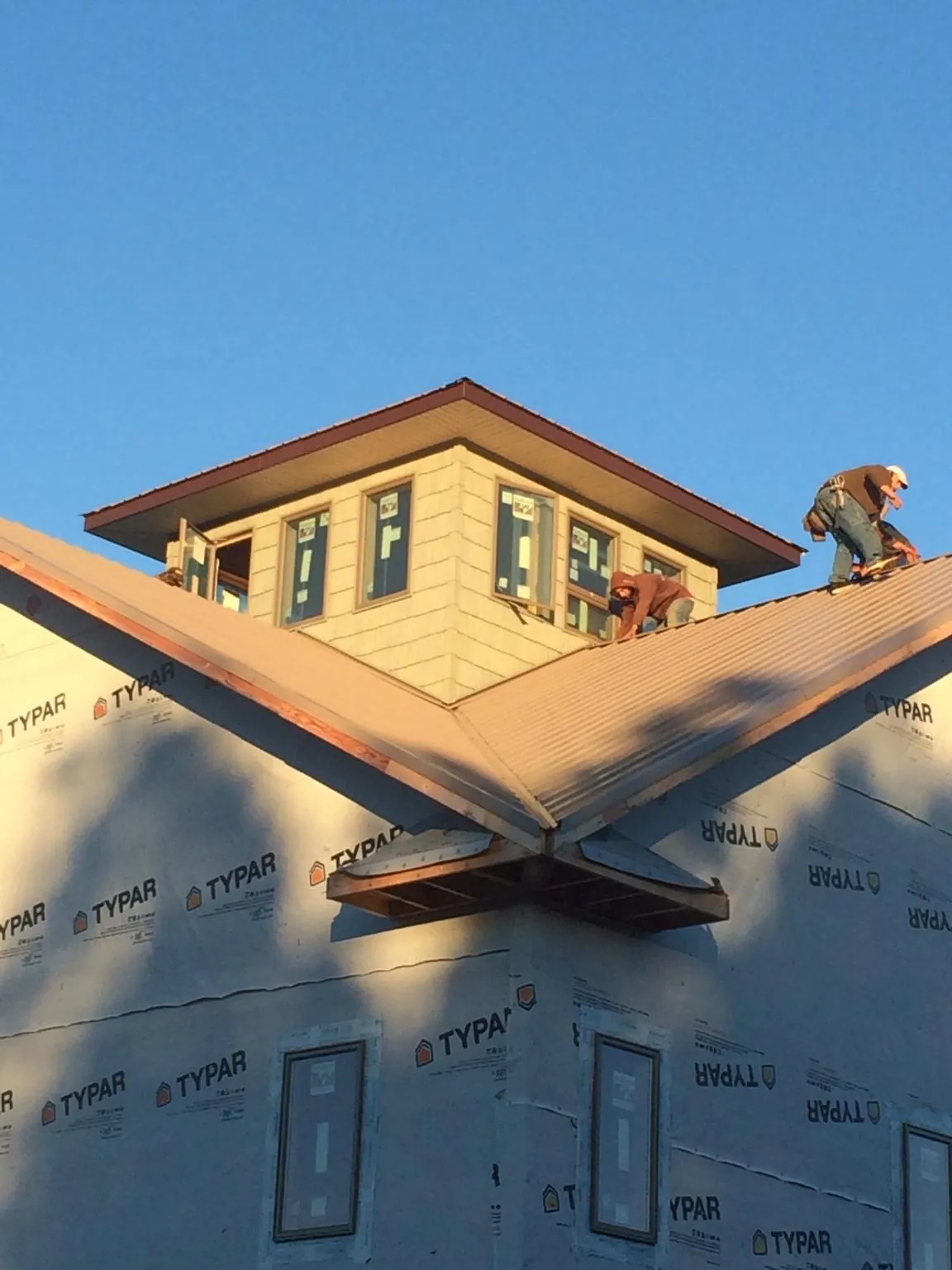 Roofers working around a rooftop cupola on a new metal roof at sunset — Roof Waterproofing in Fredericksburg by Roofing Brothers